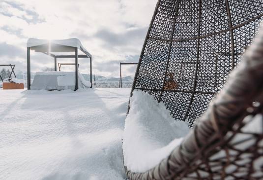 Eine Terrasse welche bedeckt von einer Schneeschicht Lust auf einen Winterurlaub in Bayern macht.