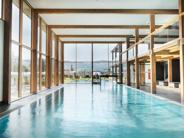 Großzügiger Wellnessbereich mit Pool vor großer Glasfront als Ort für Wellness in Oberstaufen.